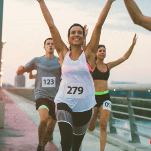 Female athlete raising hands in air as she crosses the finish line on a bridge