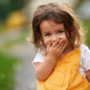 Child in yellow top. with hand over her mouth
