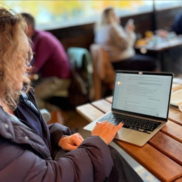 Caroline, working on her laptop in a cafe.