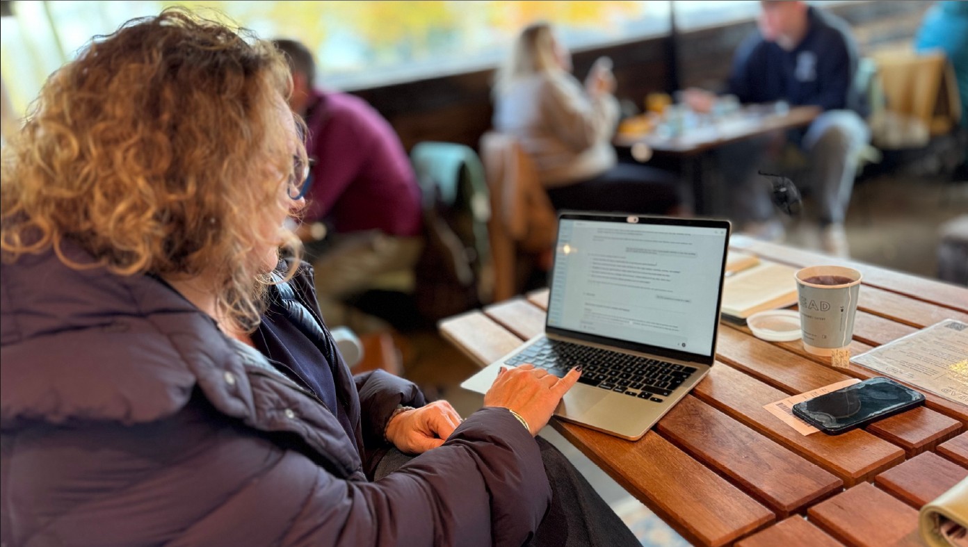 Caroline, working on her laptop in a cafe.